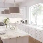 A large white kitchen with marble counter tops.