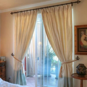 A bedroom with two windows and curtains on the same color.