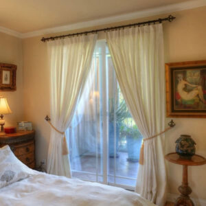 A bedroom with white curtains and a table