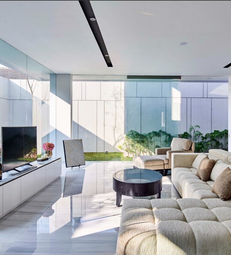 This grand living room features large-scale windows and expansive porcelain slabs, creating a seamless connection to the outdoors. The open floor plan design enhances natural light, offering a bright and spacious atmosphere.