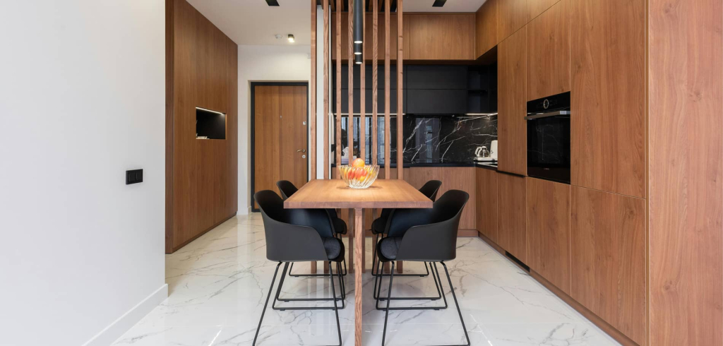 Modern small apartment kitchen featuring wood-like cabinet doors and a compact dining table. The design maximizes space with a sleek, contemporary look and functional layout.